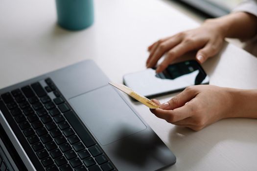 Close up woman hands holding credit card and smartphone paying online, using banking service, entering information, shopping, ordering in internet store, doing secure payment