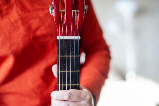 Close-up of a guitar player or a person learning to play an acoustic guitar. Home learning to play a musical instrument