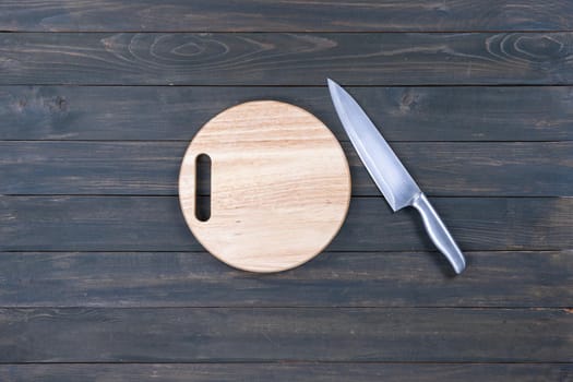 kitchen knife and wooden round empty cutting board on a wooden table close up