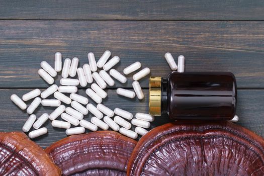 Close up of Ling zhi mushroom, Ganoderma lucidum mushroom and capsule with bottle mockup on wood table