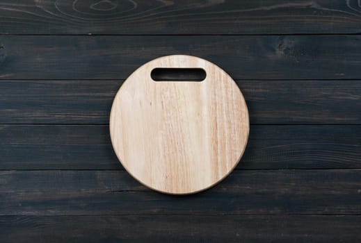 Wooden round empty cutting board on a wooden table close up