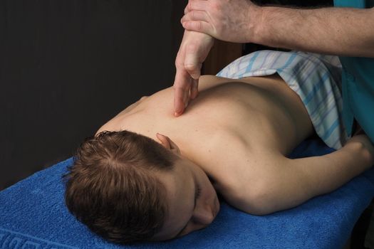 The back massage is manual. The specialist massages the back of the patient lying on the massage couch. High quality photo. High quality photo