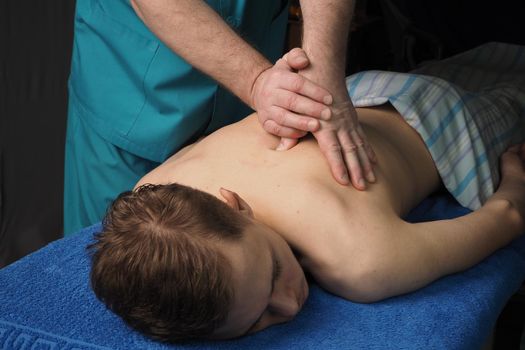 The back massage is manual. The specialist massages the back of the patient lying on the massage couch. High quality photo. High quality photo