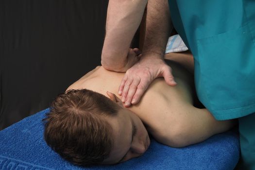 The back massage is manual. The specialist massages the back of the patient lying on the massage couch. High quality photo. High quality photo