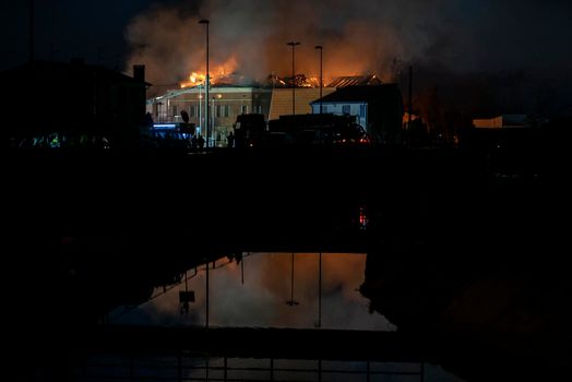 House burning at night with firefighters and smoke