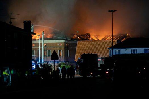 House burning at night with firefighters and smoke