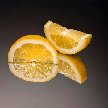 a sliced lemon on a mirror with the black background