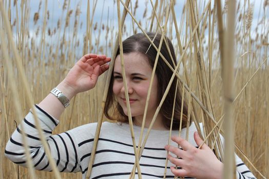 Portrait of a girl of European appearance in nature in a field against the background of high wheat. High quality photo