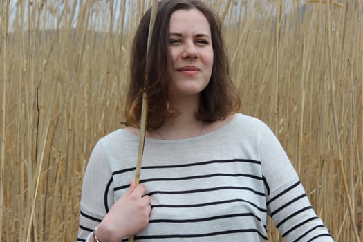 Portrait of a young girl in an outdoor field against a backdrop of wheat or tall grass. High quality photo