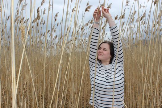 Portrait of a young girl in an outdoor field against a backdrop of wheat or tall grass. High quality photo