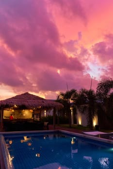 A gentle sunset sky over a thatched bungalow. An exotic resort in the tropics.