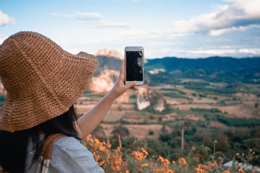 The girl take photo with smart phone on balcony bar at Phu Lang Ka mountain landmark in Phayao province Thailand