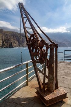 Detail of an old rusty harbour crane by the sea on a sunny day