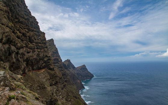 Scenic of a rocky cliff by teh sea on a sunny day