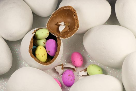 Broken white chocolate candy Easter egg filled with colorful speckled candy eggs