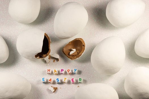 Happy Easter text beads with large white chocolate candy eggs and broken egg