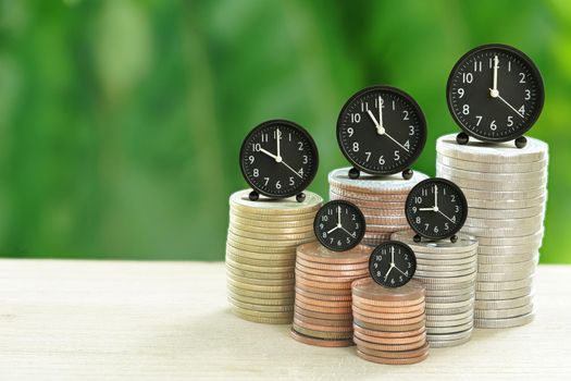 Abstract Alarm Clock and Coins stacked on your desk, time for savings ideas, banking and business concepts and with nature background.