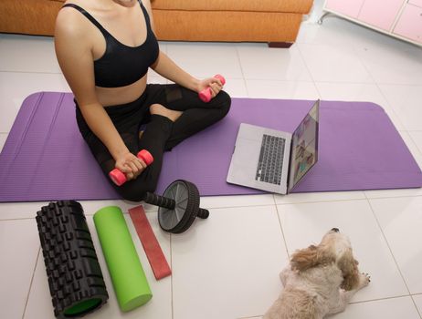 Asian woman training to lift pink dumbbells for building muscle, concept of staying healthy by weight loss and recreation at their own residence.