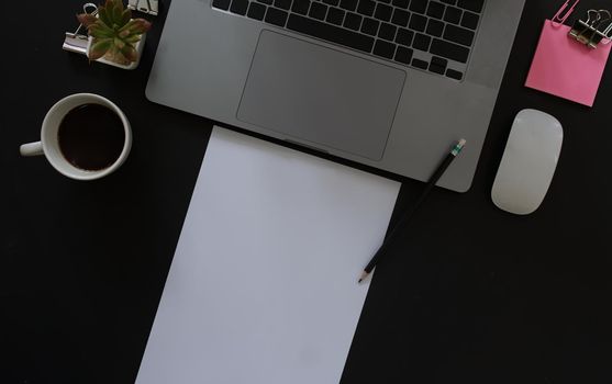 Business desk with laptop and memo paper placed on a black background, including a copy area to add text or graphics.