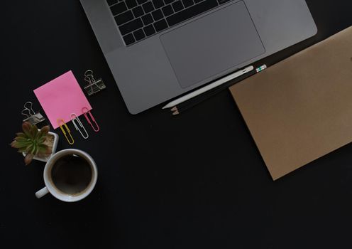 Business desk with laptop and memo paper placed on a black background, including a copy area to add text or graphics.