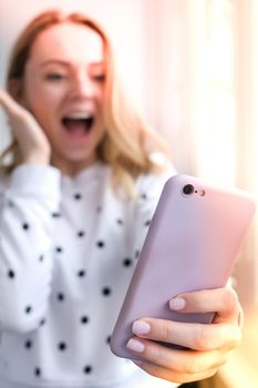 Blonde young girl taking selfie. Video call. Online education. Work from home. Woman holding smartphone. Phone call. Recording new vlog for her channel. Blogger Conference surprised