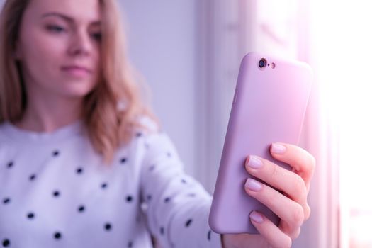 Blonde young girl taking selfie. Video call. Online education. Work from home. Woman holding smartphone. Phone call. Recording new vlog for her channel. Blogger Conference