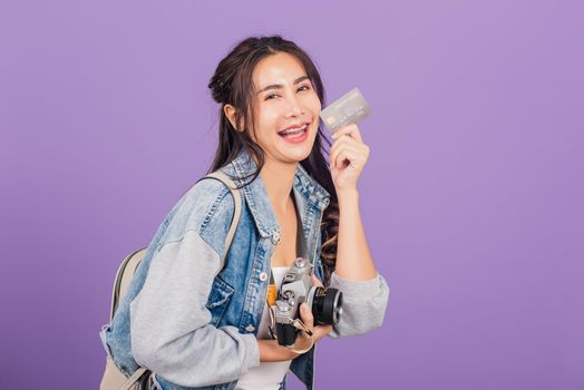 Happy Asian portrait beautiful young woman excited smiling photographer holding debit credit card bank and retro vintage photo camera ready travel isolated on purple background, tourism and vacation