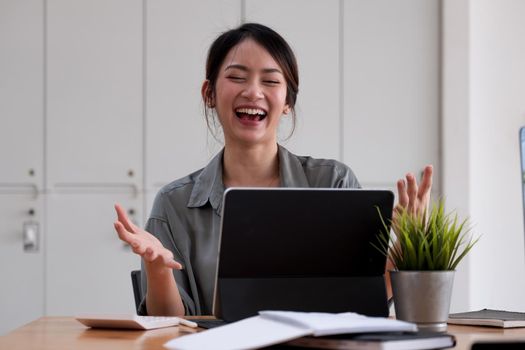 Portrait of an excited young asian girl using laptop computer and celebrating success for online learning or working at home.