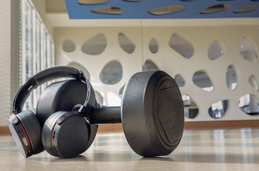 Headphones and Dumbbell  for Listening to music while exercising at Fitness studio. Copy space, Selective focus.