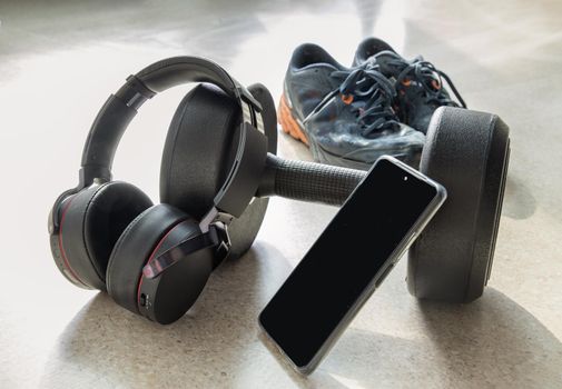 Composition of Dumbbell and Sports shoes with Smartphone and Headphones for Listening to music while exercising. Copy space, Selective focus.