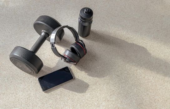 Composition of Smartphone and Headphones, Dumbbell and water bottle for Listening to music while exercising. Copy space, Selective focus.