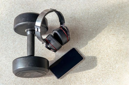 Composition of Smartphone, Headphones and Dumbbell for Listening to music while exercising. Copy space, Selective focus.