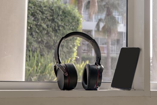 Smartphone and Headphones for listening to music Placed on glass wall In the time of rest. Personal device with Space for text. Selective focus.
