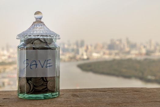The pile of coins in glass bottle on cityscape background for concept for growth and saving money. Space for text input, Selective focus.