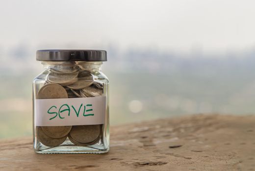 The pile of coins in glass bottle on sky background for concept for growth and saving money. Space for text input, Selective focus.