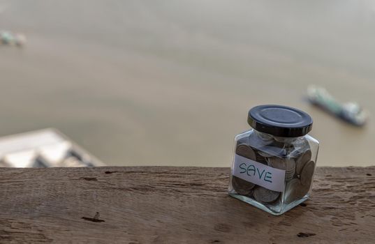 The pile of coins in glass bottle on river background for concept for growth and saving money. Space for text input, Selective focus.
