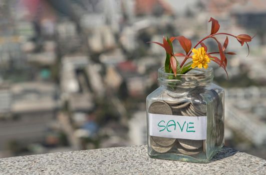 The pile of coins in glass bottle on cityscape background for concept for growth and saving money. Space for text input, Selective focus.