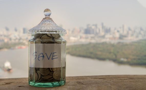 The pile of coins in glass bottle on cityscape background for concept for growth and saving money. Space for text input, Selective focus.