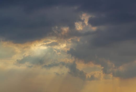 The sun's rays passing through the clouds and shining form an interesting light pattern against the sky evening. Copy space, No focus, specifically.