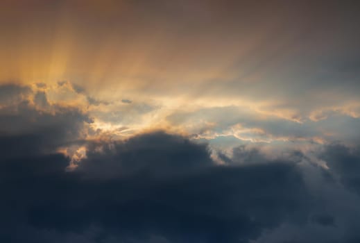 The sun's rays passing through the clouds and shining form an interesting light pattern against the sky evening. Copy space, No focus, specifically.