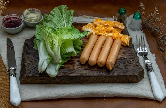 Continental breakfast with scrambled eggs, fried sausages, vegetable and scones on Wooden background, Selective focuse.