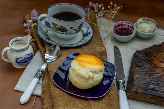 Scones with mascarpone cheese and raspberry jam served with black coffee with milk on sack cloth for new morning. Selective focuse.