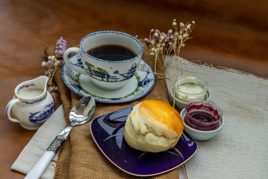 Scones with mascarpone cheese and raspberry jam served with black coffee with milk on sack cloth for new morning. Selective focuse.
