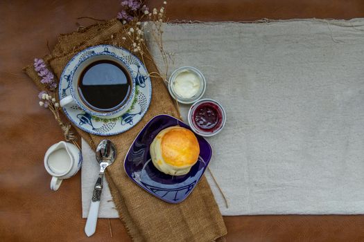 Scones with mascarpone cheese and raspberry jam served with black coffee with milk on sack cloth for new morning. Selective focuse.