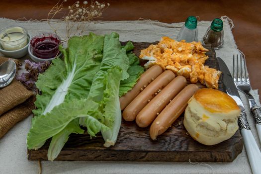 Continental breakfast with scrambled eggs, fried sausages, vegetable and scones on Wooden background, Selective focuse.