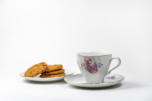 Dry biscuit biscuits from the package lie on a saucer next to a cup for tea