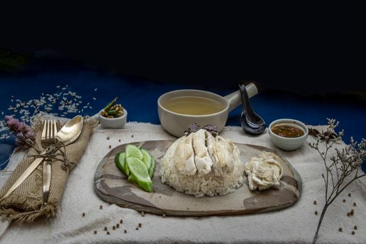 Hainanese chicken rice (Steam chicken with rice) with cucumber closeup on a plate and broth.