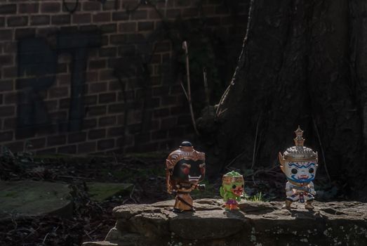 Ravana, Giantess and Hanuman Standing on a stone fence around a large tree In the cemetery. Traveller doll.