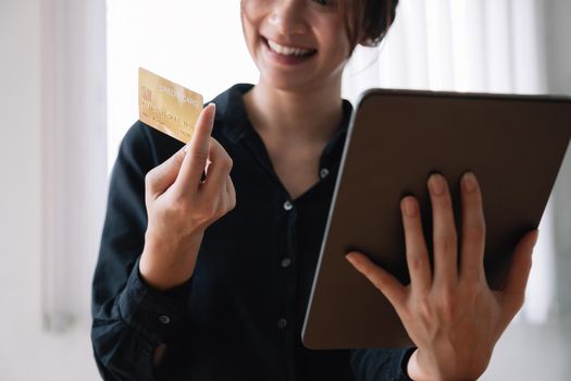 Asian woman making online payment using laptop and credit card for shopping at home