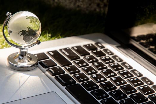 Glass crystal globe on Laptop keyboard. Concept for global communication and business. Selective focus.